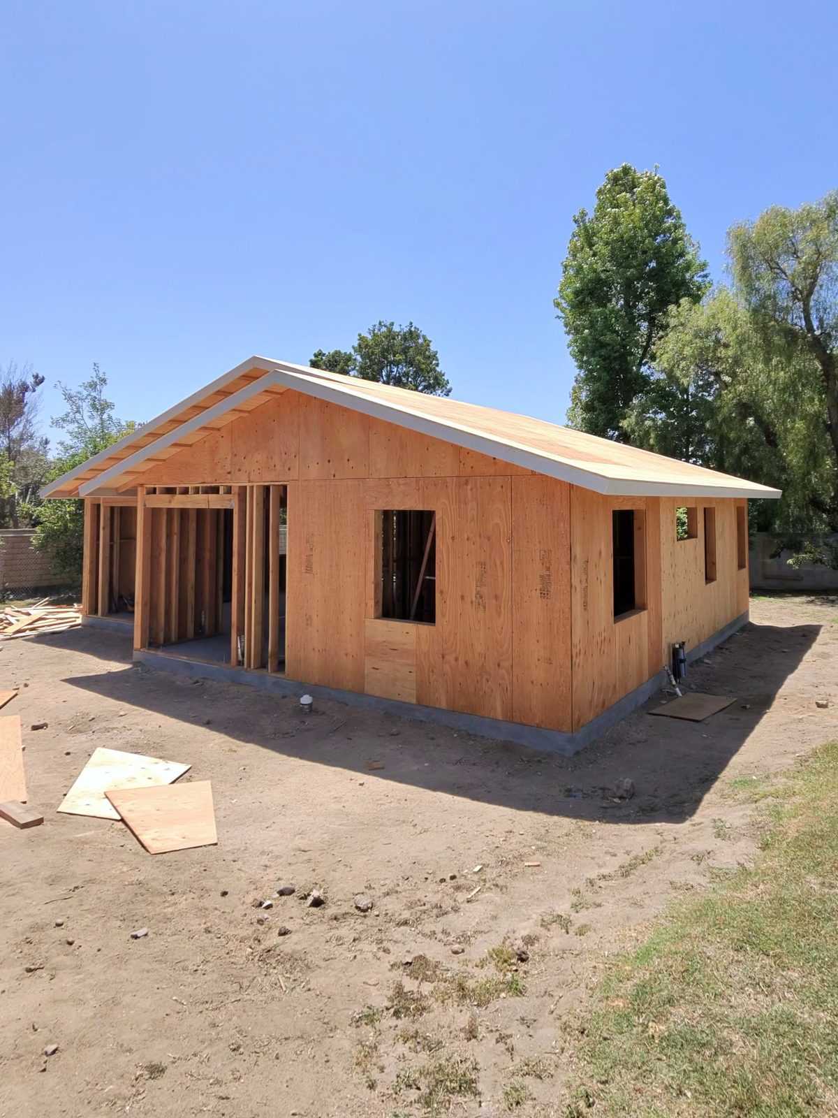 Small framed structure with completed roof sheathing under a blue sky