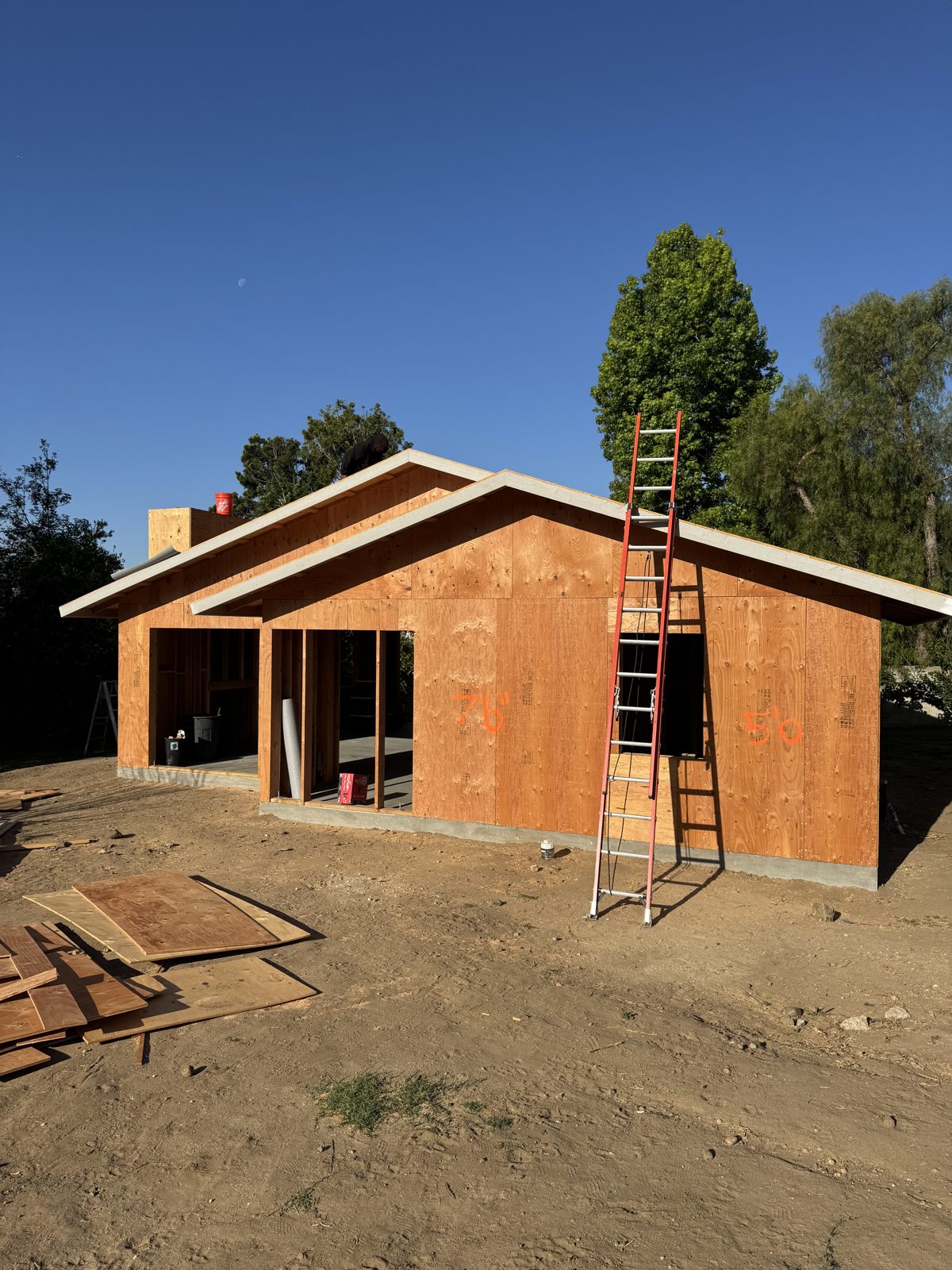 ADU fully framed and sheathed at golden hour with ladder set against the wall