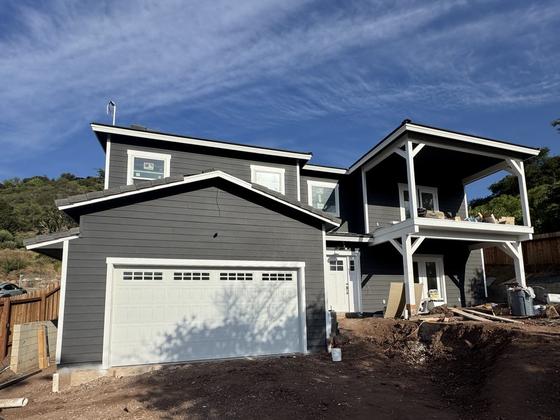 New custom home with dark board-and-batten siding, white trim, and carriage garage door