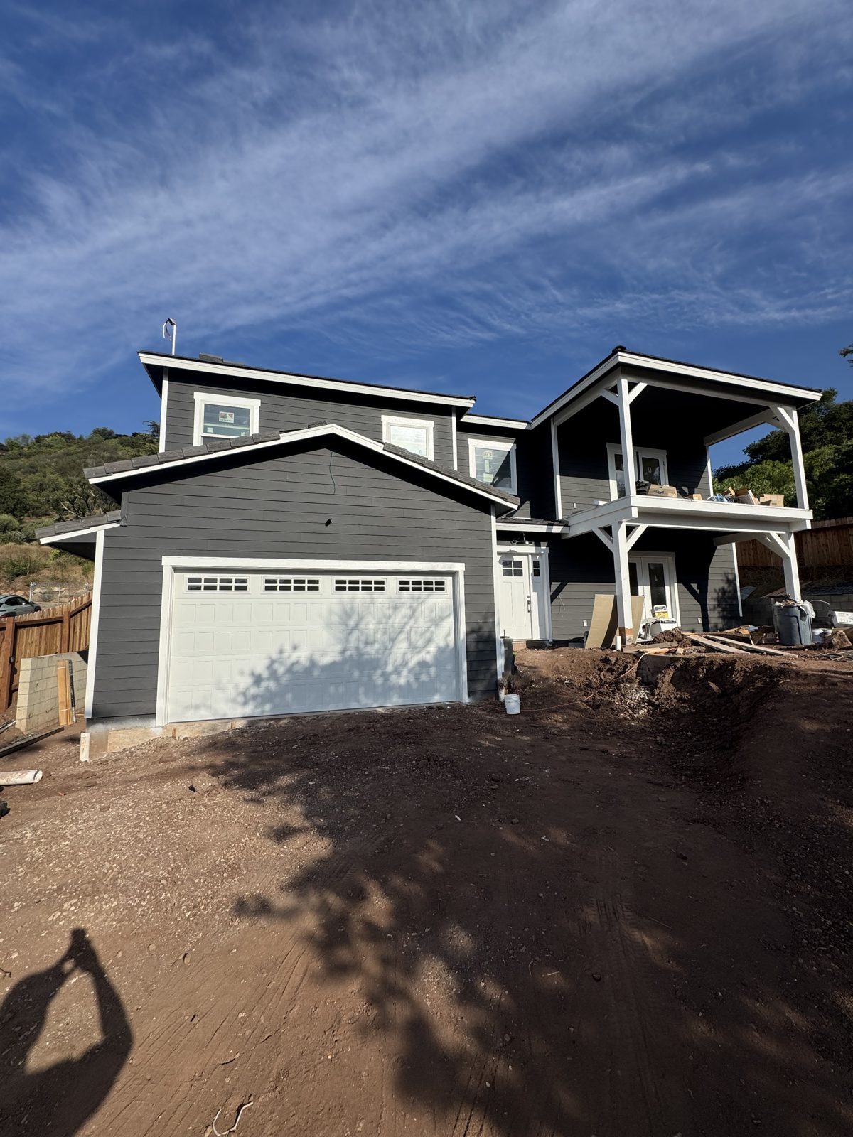 New custom home with dark board-and-batten siding, white trim, and carriage garage door nearly complete