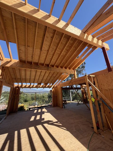 Exposed rafter and beam roof framing on a hillside custom home with mountain views