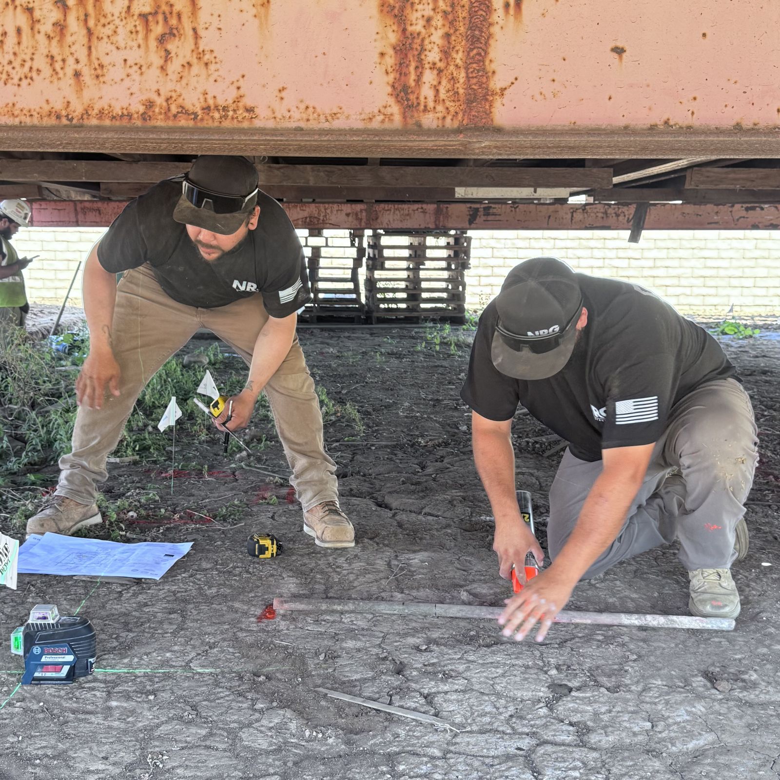 NRG crew doing laser layout for a new foundation under a lifted structure