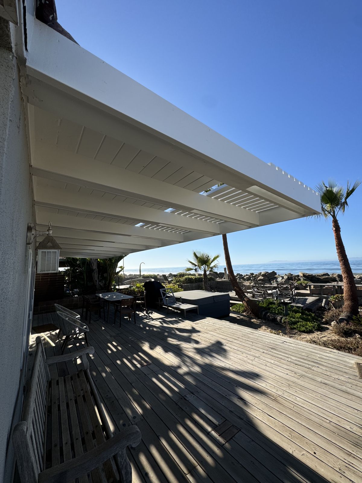 Finished patio cover with exposed beams over an oceanfront deck