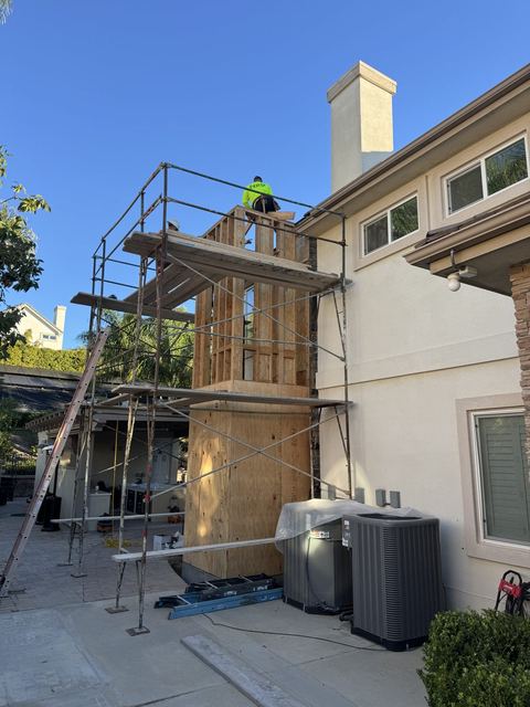 NRG crew framing a residential elevator shaft on an occupied stucco home