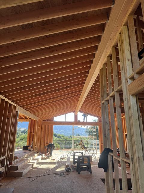 Vaulted great room with exposed rafter framing and hillside views